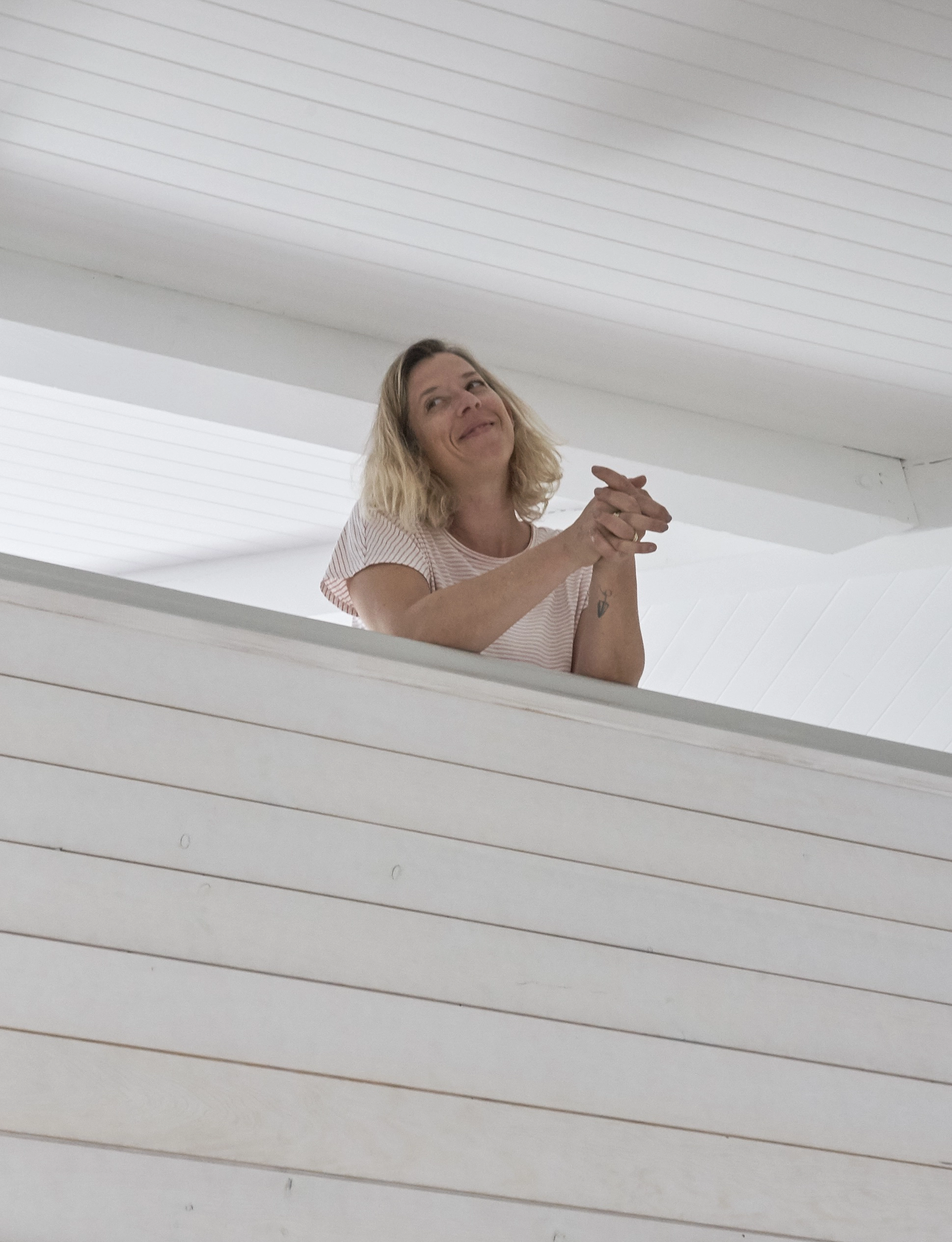 Jeune femme blonde souriante sur un rebord intérieur blanc